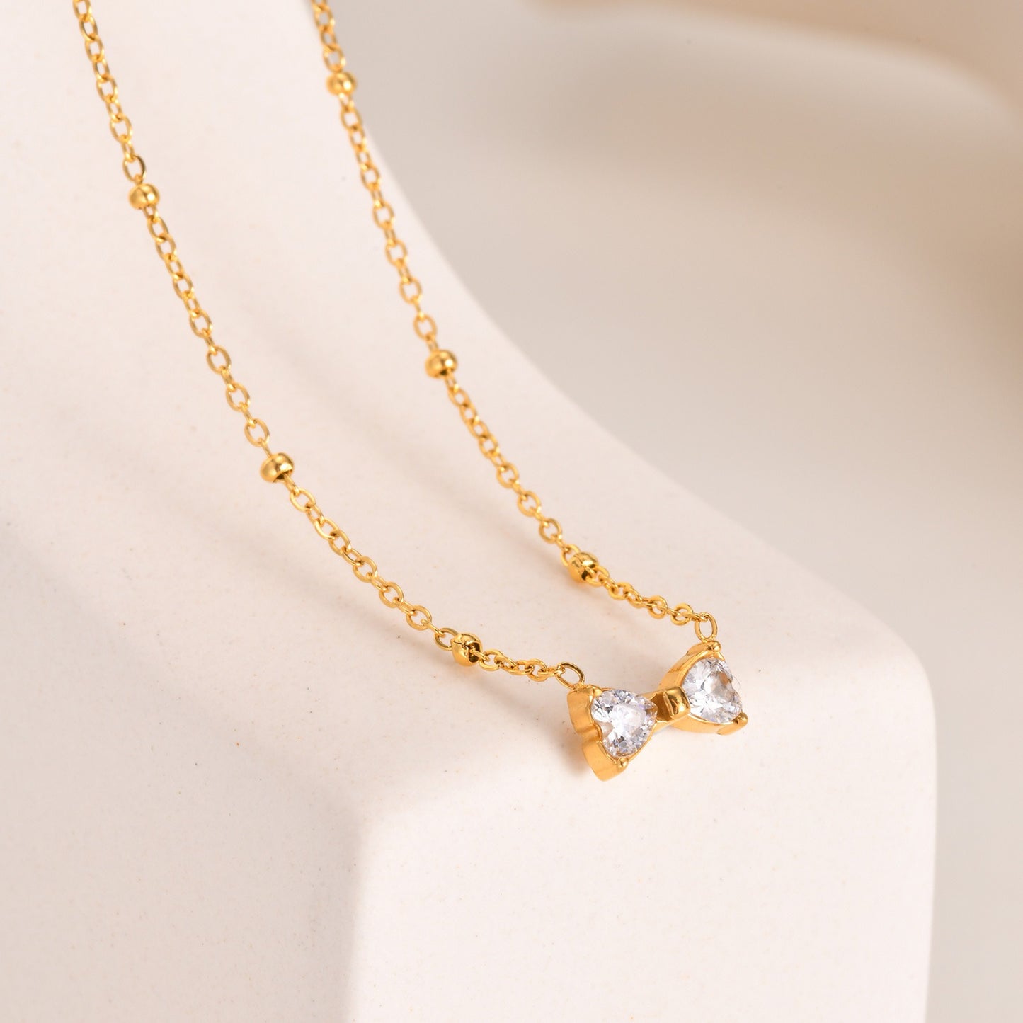 Delicado collar de lazo de acero inoxidable Kemstone con circonitas de cristal y cadena de cuentas. Joyería minimalista en tono dorado para mujer. NC-1718
