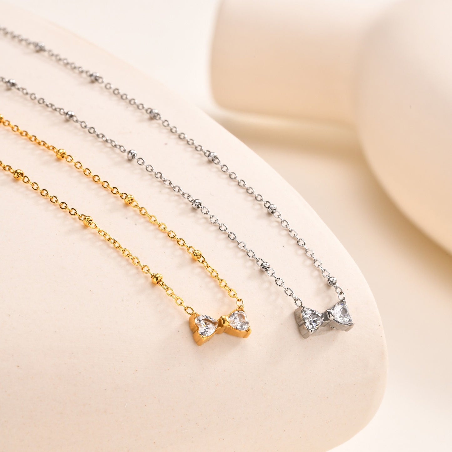 Delicado collar de lazo de acero inoxidable Kemstone con circonitas de cristal y cadena de cuentas. Joyería minimalista en tono dorado para mujer. NC-1718