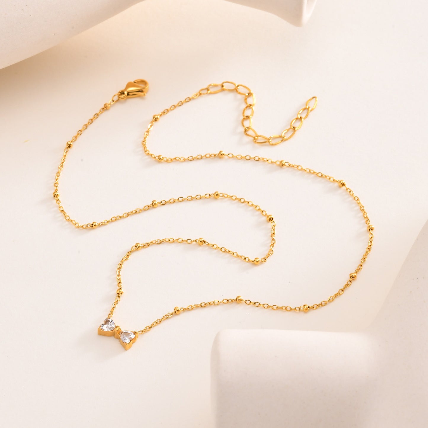 Delicado collar de lazo de acero inoxidable Kemstone con circonitas de cristal y cadena de cuentas. Joyería minimalista en tono dorado para mujer. NC-1718