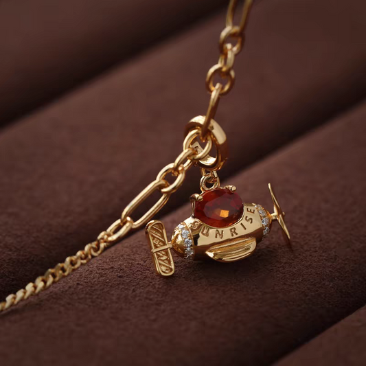 Collar de avión con diseño original de Kemstone, hecho a mano y con diseño de amanecer. Colgante original de avión con granate espesartita en plata de ley 925. Cadena ajustable bañada en oro. Un regalo único para mujer.