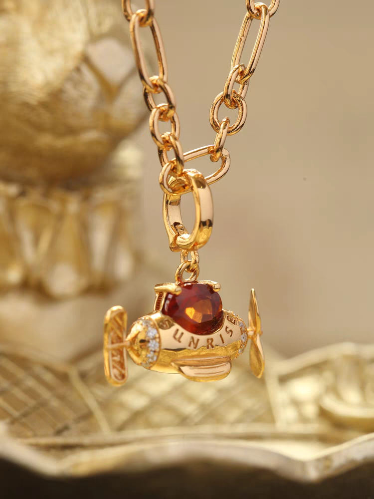 Collar de avión con diseño original de Kemstone, hecho a mano y con diseño de amanecer. Colgante original de avión con granate espesartita en plata de ley 925. Cadena ajustable bañada en oro. Un regalo único para mujer.