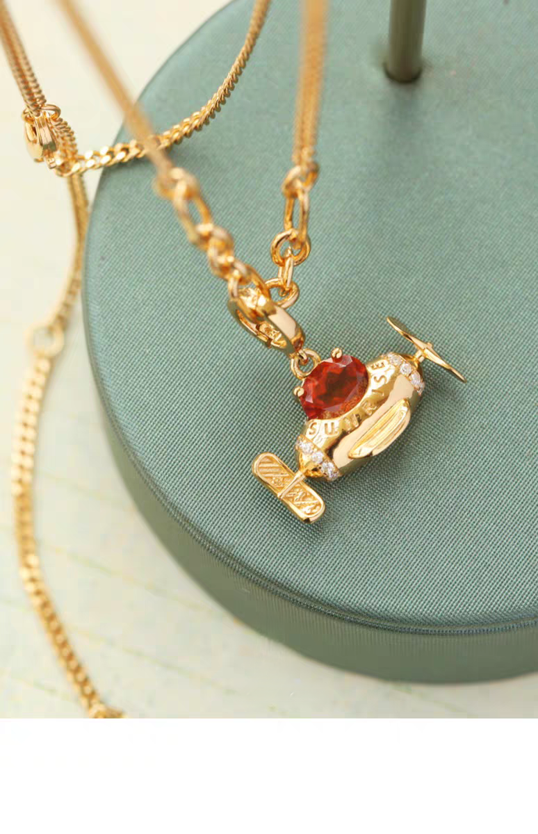 Collar de avión con diseño original de Kemstone, hecho a mano y con diseño de amanecer. Colgante original de avión con granate espesartita en plata de ley 925. Cadena ajustable bañada en oro. Un regalo único para mujer.